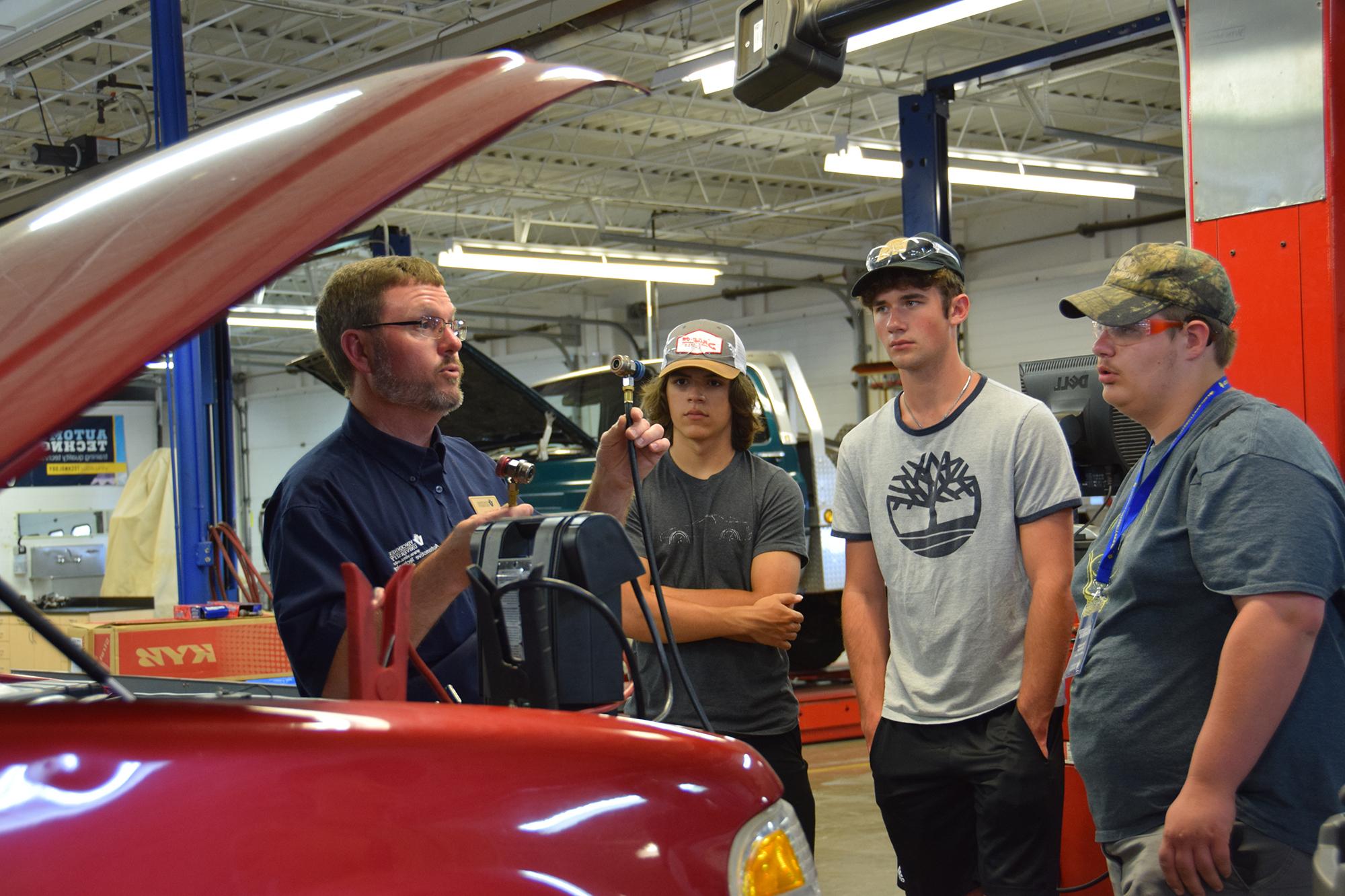 Automotive club students meet with their instructor