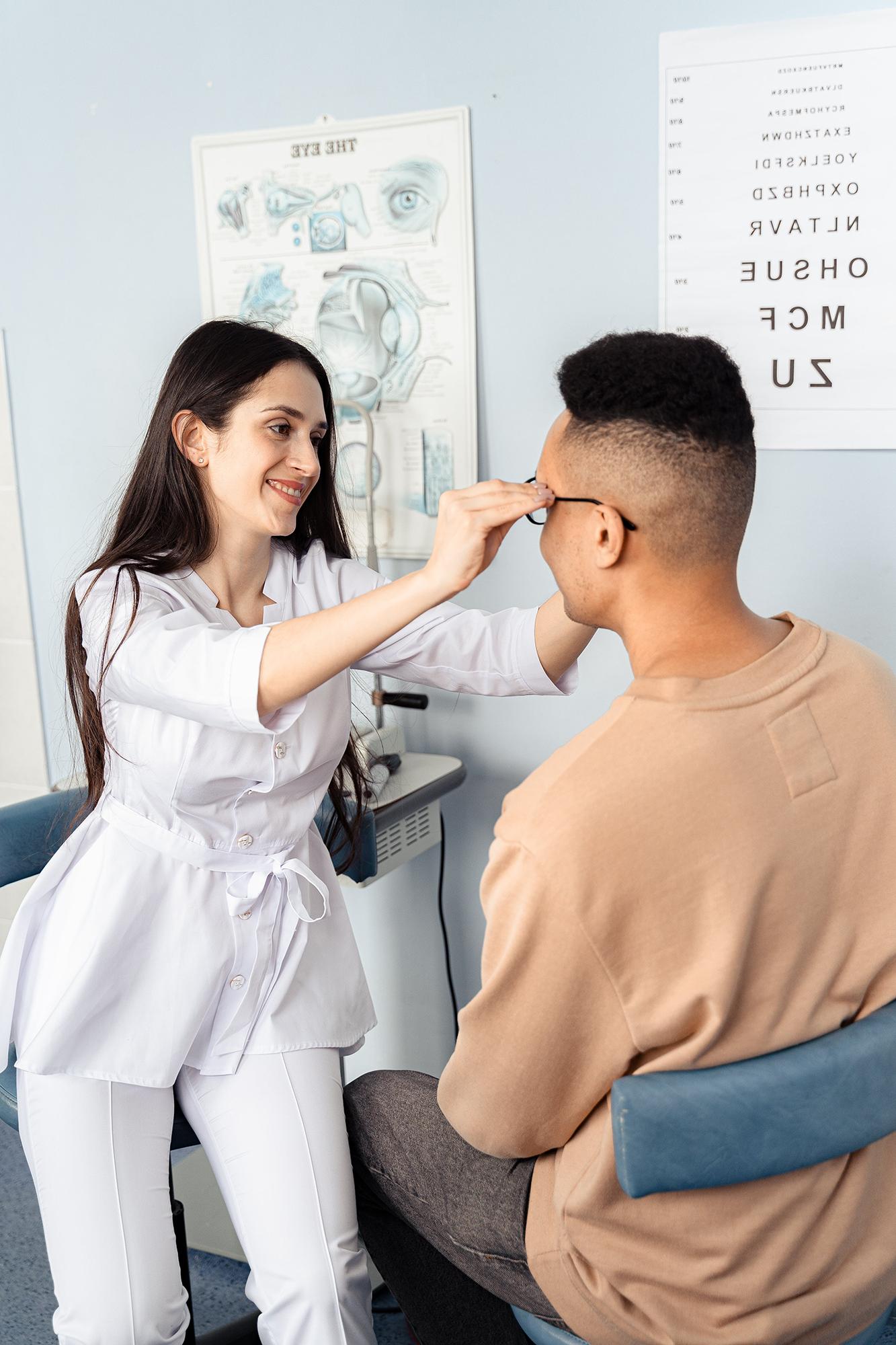 An optometrist putting a pair of glasses on her client's face