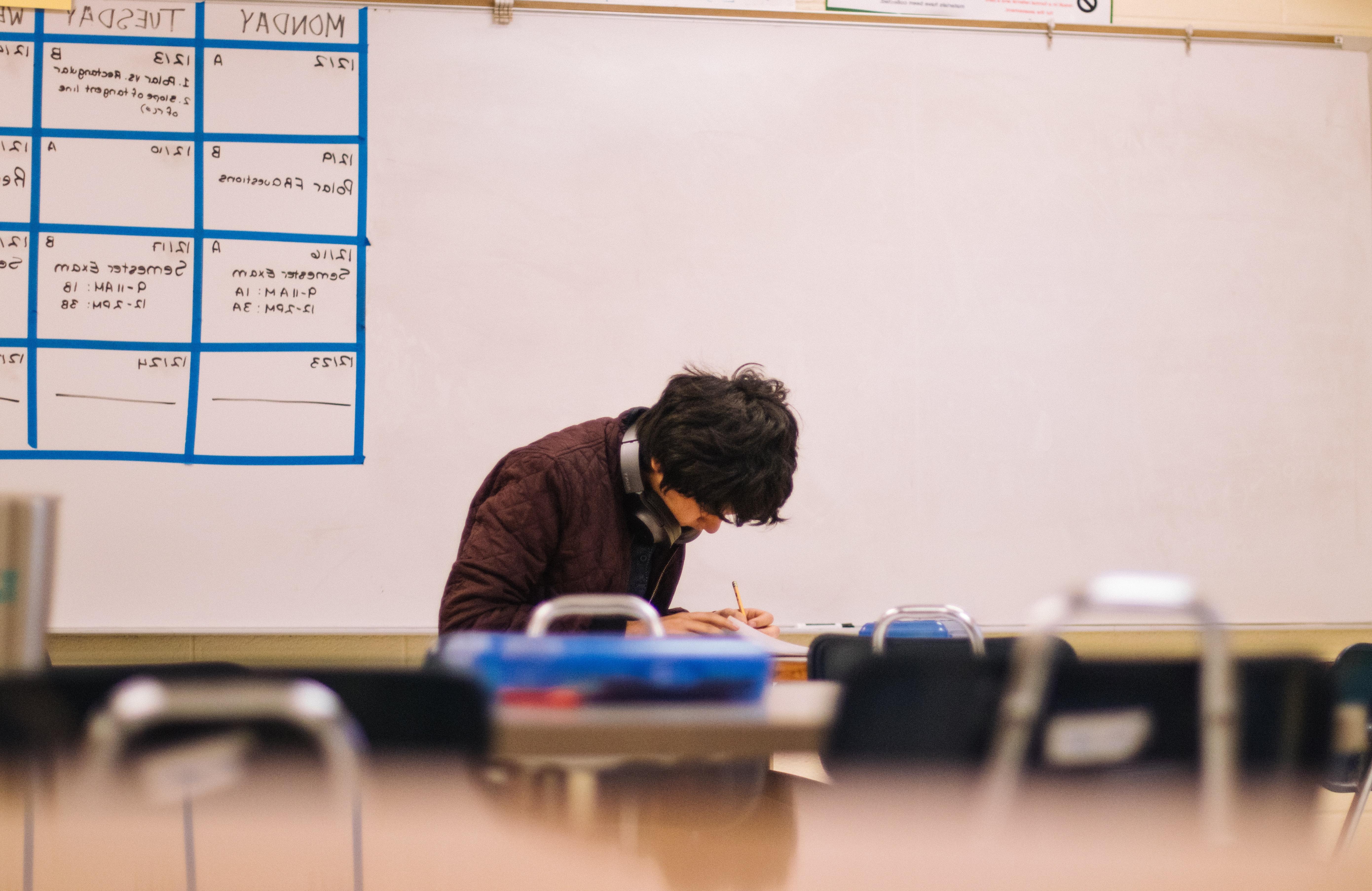 A student sitting alone at his desk while he completes an assignment