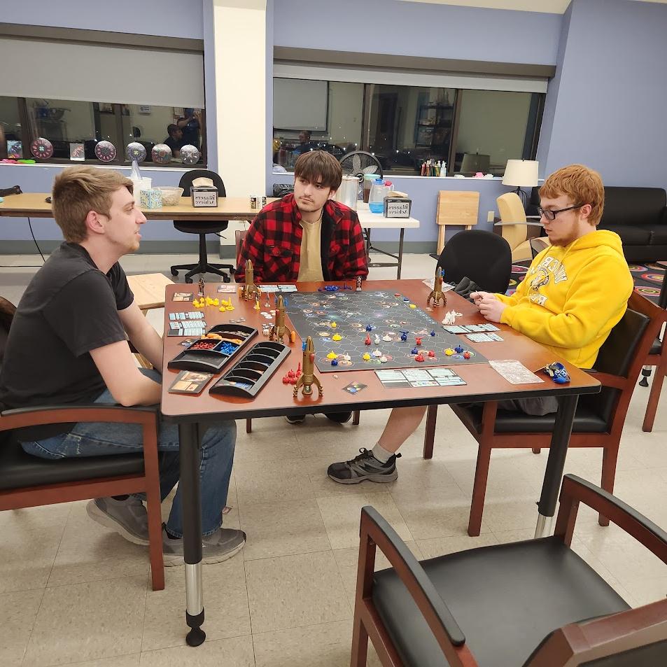 Three students playing a board game together