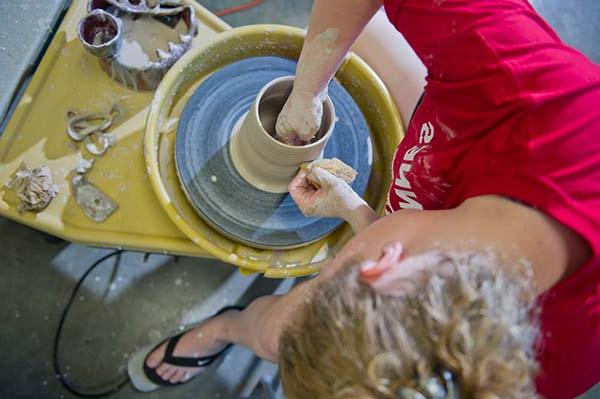 Student works clay on a pottery wheel