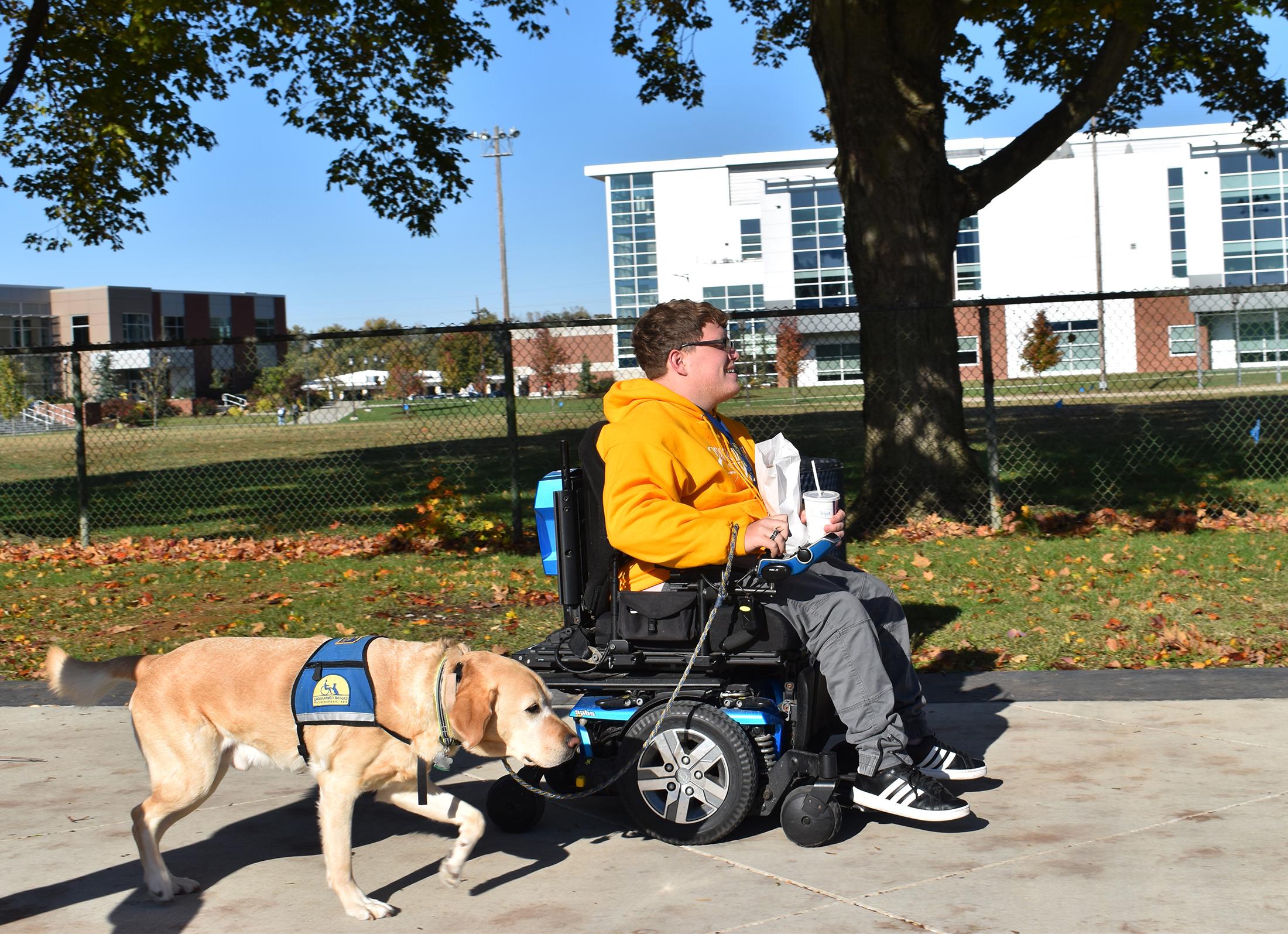 A student walking with his service dog in front of Updike Hall