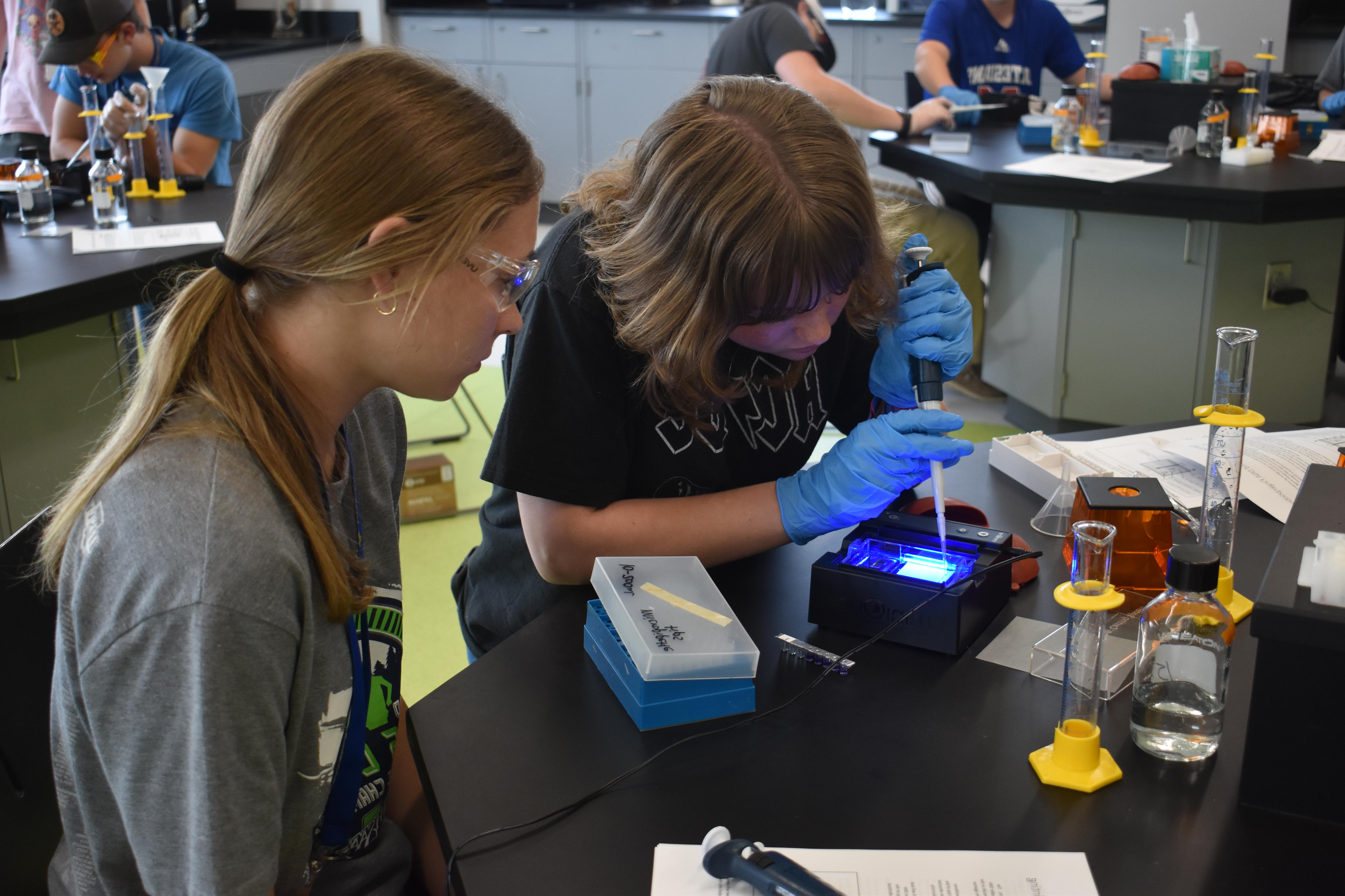 在科学实验室里，女学生们用移液管将液体滴入小瓶中，进行科学实验.
